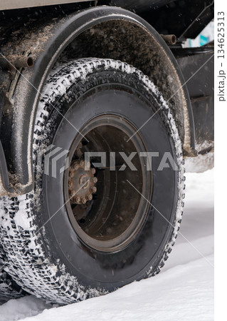 Black wheel of a truck on snow in winter. 134625313