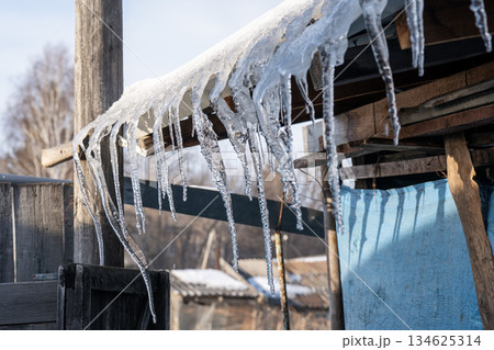 Icicles hanging from the roof of a barn. Icicles hanging from the roof of a barn. 134625314