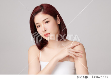 A beautiful young Asian woman with clean, fresh skin against a grey background. Skincare, facial treatment, cosmetology, beauty, and spa. An elegant portrait of an Asian woman. A beautiful young Asian woman with clean, fresh skin against a grey background. Skincare, facial treatment, cosmetology, beauty, and spa. An elegant portrait of an Asian woman. 134625645
