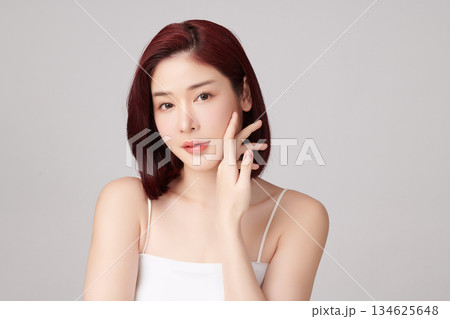 A beautiful young Asian woman with clean, fresh skin against a grey background. Skincare, facial treatment, cosmetology, beauty, and spa. An elegant portrait of an Asian woman. A beautiful young Asian woman with clean, fresh skin against a grey background. Skincare, facial treatment, cosmetology, beauty, and spa. An elegant portrait of an Asian woman. 134625648