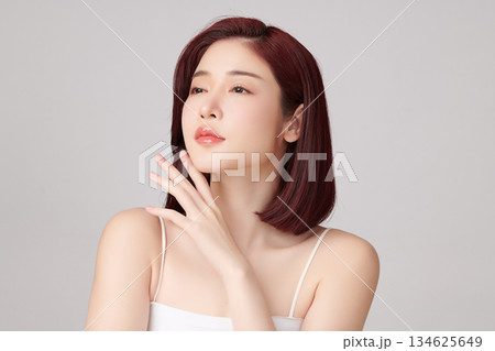 A beautiful young Asian woman with clean, fresh skin against a grey background. Skincare, facial treatment, cosmetology, beauty, and spa. An elegant portrait of an Asian woman. A beautiful young Asian woman with clean, fresh skin against a grey background. Skincare, facial treatment, cosmetology, beauty, and spa. An elegant portrait of an Asian woman. 134625649