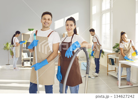 Male, female cleaners posing, group working, professional janitor service busy completing cleaning Male, female cleaners posing, group working, professional janitor service busy completing cleaning 134627242