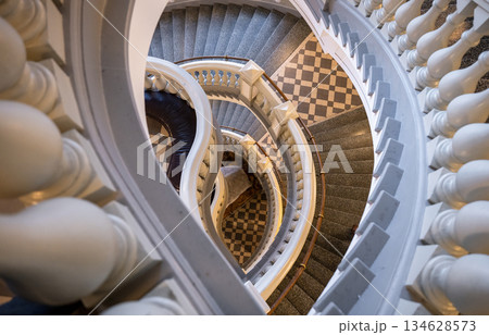 Elegant spiral staircase with classic balustrade and tiled floor Elegant spiral staircase with classic balustrade and tiled floor 134628573