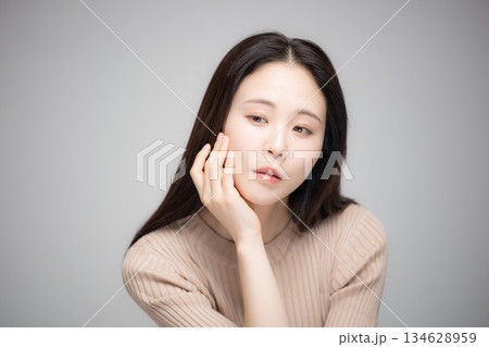 顎に手を当てて考えるアンニュイな表情の美人な女性　カメラ目線	 134628959