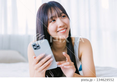 ベッドでスマホを使う若い女性 134629552