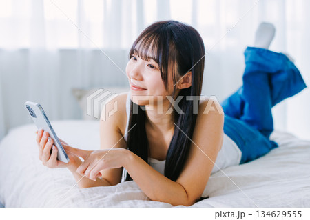 ベッドでスマホを使う若い女性 134629555