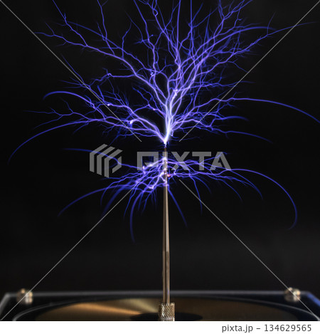 A bright electrostatic discharge from a Tesla coil with blue branching lightning bolts 134629565
