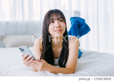 ベッドでスマホを使う若い女性 134629600