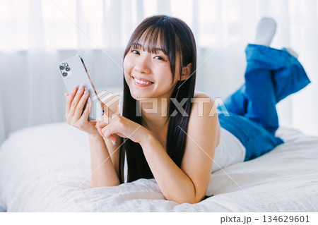 ベッドでスマホを使う若い女性 134629601