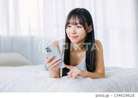 ベッドでスマホを使う若い女性 134629628