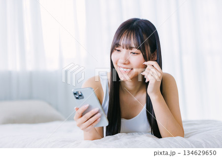 ベッドでスマホを使う若い女性 134629650