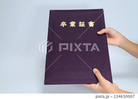 卒業証書カバーを持つ子供の手とコピースペース 134630007