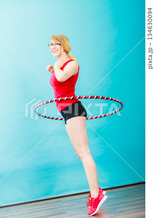 Fit woman with hula hoop doing exercise 134630094