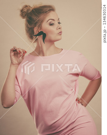 Happy woman holding fake moustache on stick 134630314