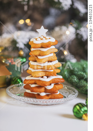 Christmas Tree Cookie Stack with Icing and Ornaments on White Table Christmas Tree Cookie Stack with Icing and Ornaments on White Table 134631215