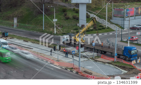 Loader crane for loading and unloading tram rails from truck which stands on a road construction site aerial timelapse Loader crane for loading and unloading tram rails from truck which stands on a road construction site aerial timelapse 134631399