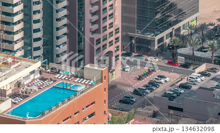 Car parking lot with rooftop swimming pool viewed from above timelapse, Aerial top view. Dubai, UAE Car parking lot with rooftop swimming pool viewed from above timelapse, Aerial top view. Dubai, UAE 134632098