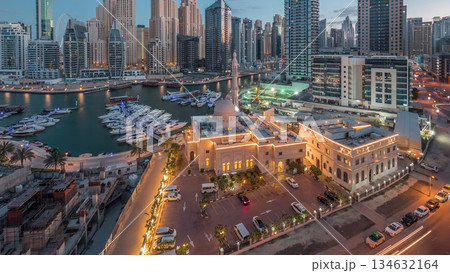 Yachts in Dubai Marina flanked by the Al Rahim Mosque and residential towers and skyscrapers aerial night to day timelapse. Yachts in Dubai Marina flanked by the Al Rahim Mosque and residential towers and skyscrapers aerial night to day timelapse. 134632164
