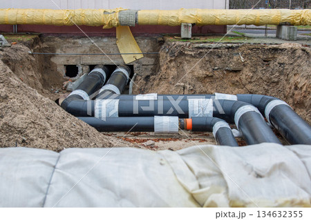 Insulated district heating pipes installation in deep urban trench Insulated district heating pipes installation in deep urban trench 134632355