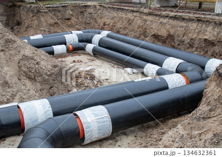 Insulated district heating pipes installation in deep urban trench Insulated district heating pipes installation in deep urban trench 134632361