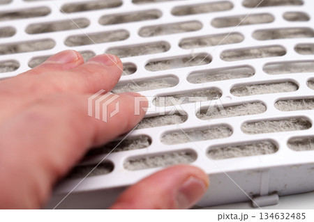 Air filter element clogged with dust fibers touched by a human hand. Used filtration cartridge 134632485
