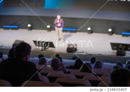 Speaker on stage addressing audience at a conference in a large hall Speaker on stage addressing audience at a conference in a large hall 134633407