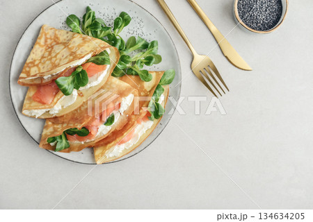 Crepes or thin pancakes with lightly salted salmon, soft cheese and cornsalad Crepes or thin pancakes with lightly salted salmon, soft cheese and cornsalad 134634205