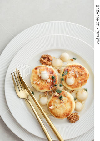 cottage cheese pancakes, syrniki, curd fritters served with pear balls, walnut and honey 134634210