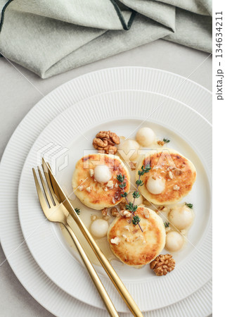 cottage cheese pancakes, syrniki, curd fritters served with pear balls, walnut and honey 134634211