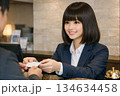 チェックインのお客にカードキーを渡すおかっぱボブのフロントの女性 134634458