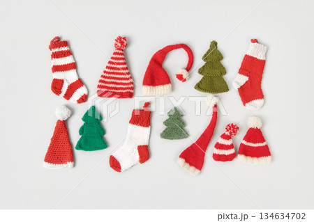 Knitted Christmas toys in form of red and white socks, Santa Claus hats, green Christmas trees on gray background. Top view, flat lay. Knitted Christmas toys in form of red and white socks, Santa Claus hats, green Christmas trees on gray background. Top view, flat lay. 134634702