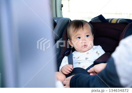 子どもをチャイルドシートに座らせる母親　自動車のチャイルドシートに座る赤ちゃん　後部座席　安全確認 134634872