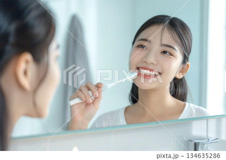 明るい洗面所で歯ブラシを持って白い歯を見せて微笑む若い女性 明るい洗面所で歯ブラシを持って白い歯を見せて微笑む若い女性 134635286