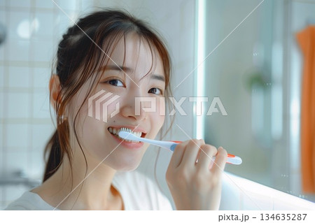 明るい洗面所で歯ブラシを持って白い歯を見せて微笑む若い女性 明るい洗面所で歯ブラシを持って白い歯を見せて微笑む若い女性 134635287