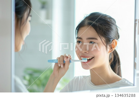 明るい洗面所で歯ブラシを持って白い歯を見せて微笑む若い女性 明るい洗面所で歯ブラシを持って白い歯を見せて微笑む若い女性 134635288