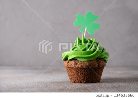 St. Patrick's Day cupcake with green whipped cream decorated clover on gray background. Copy space. Close up. Festive food. 134635660