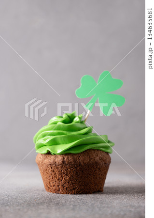 St. Patrick's Day cupcake with green whipped cream decorated clover on gray background. Sweet dessert and festive food for party. 134635681