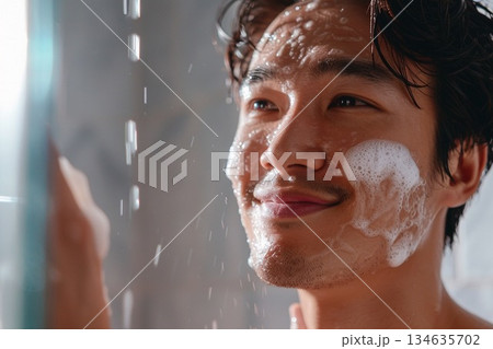 明るい洗面所でたっぷりの泡を使って洗顔をする清潔感のある若い男性 134635702