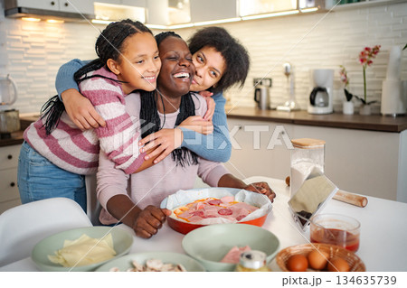 Black mother and daughters enjoying cooking pizza together 134635739