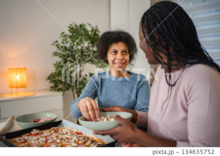 Mother and daughter cooking pizza together at home 134635752