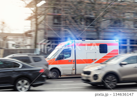 Ambulance flash emergency lights driving fast busy city traffic jam motion blur among cars urban road. Urgent medical response scene shows rescue transport public safety service rapid European city Ambulance flash emergency lights driving fast busy city traffic jam motion blur among cars urban road. Urgent medical response scene shows rescue transport public safety service rapid European city 134636147