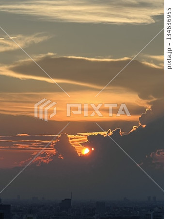 雲間に沈む夕日と街並みのシルエット 134636955