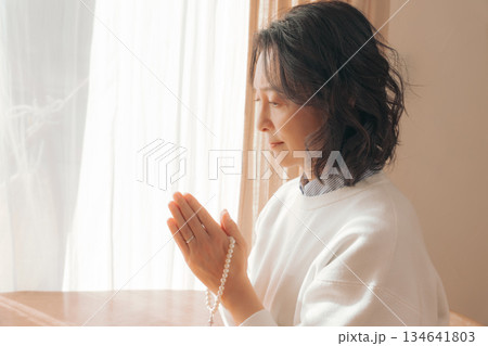 自宅で故人に祈りを捧げるミドル女性 自宅で故人に祈りを捧げるミドル女性 134641803