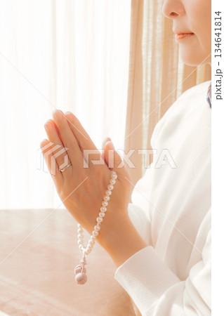 自宅で故人に祈りを捧げるミドル女性 自宅で故人に祈りを捧げるミドル女性 134641814