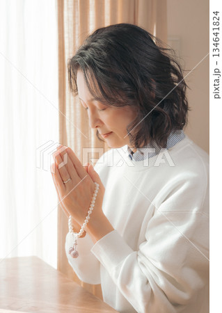 自宅で故人に祈りを捧げるミドル女性 134641824