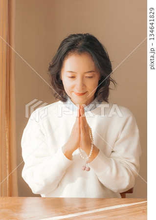 自宅で故人に祈りを捧げるミドル女性 134641829
