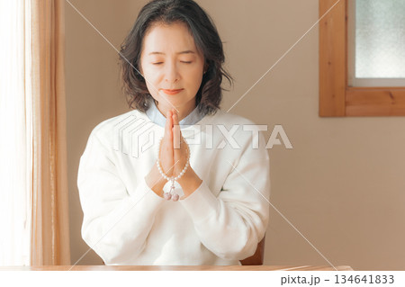 自宅で故人に祈りを捧げるミドル女性 134641833