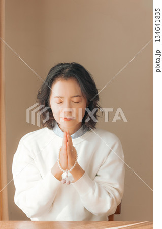 自宅で故人に祈りを捧げるミドル女性 134641835