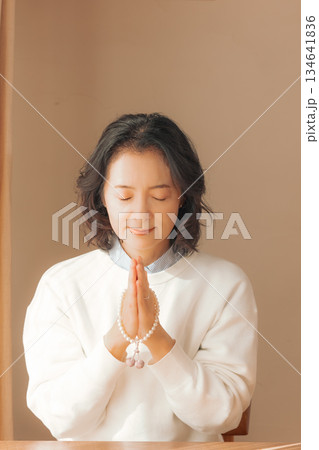 自宅で故人に祈りを捧げるミドル女性 134641836
