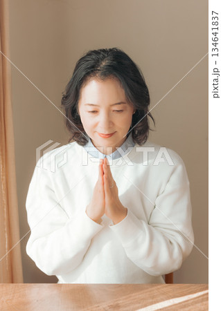 自宅で故人に祈りを捧げるミドル女性 134641837